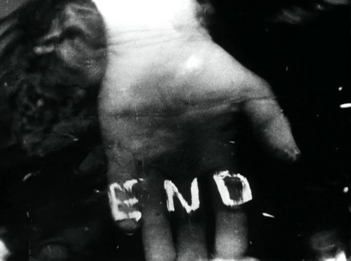 Fireworks (1947) movie still: closeup — A close-up shot of a human palm held open against a dark background. The word END is crudely painted in…