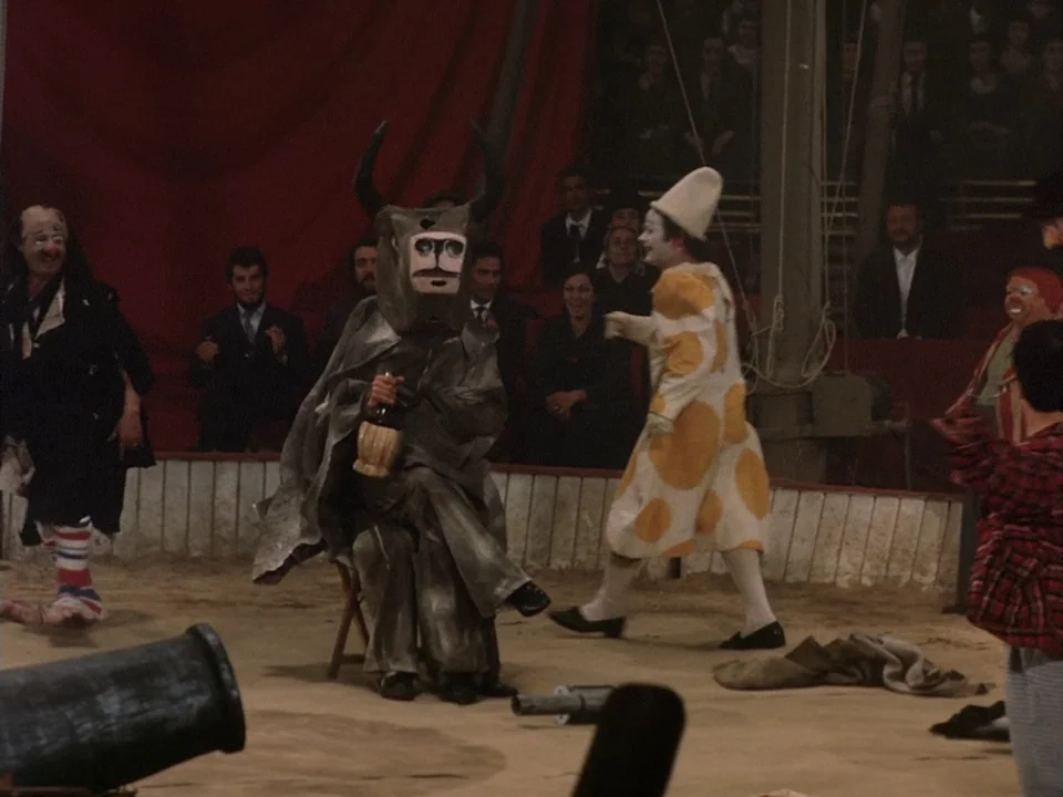 The Clowns (1970) movie still: fullbody — A sawdust-covered performance area features performers in elaborate costumes inside a large circus tent. A…