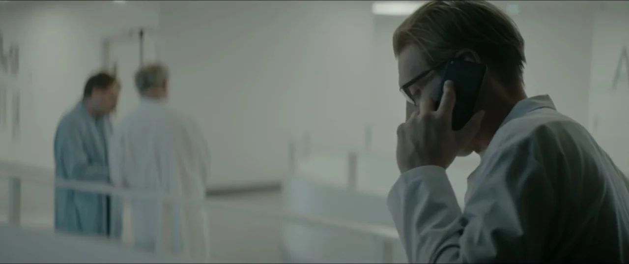 Dogs Don't Wear Pants (2019) movie still: medium — A stark white, modern hospital corridor features smooth minimalist walls and bright fluorescent…
