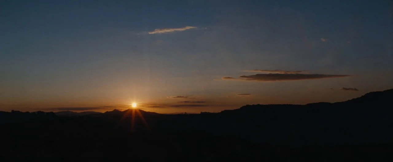 Nocturnal Animals (2016) movie still: establishing — A dark, rolling mountain range sits silhouetted against a fading dusk sky. The sun dips below…