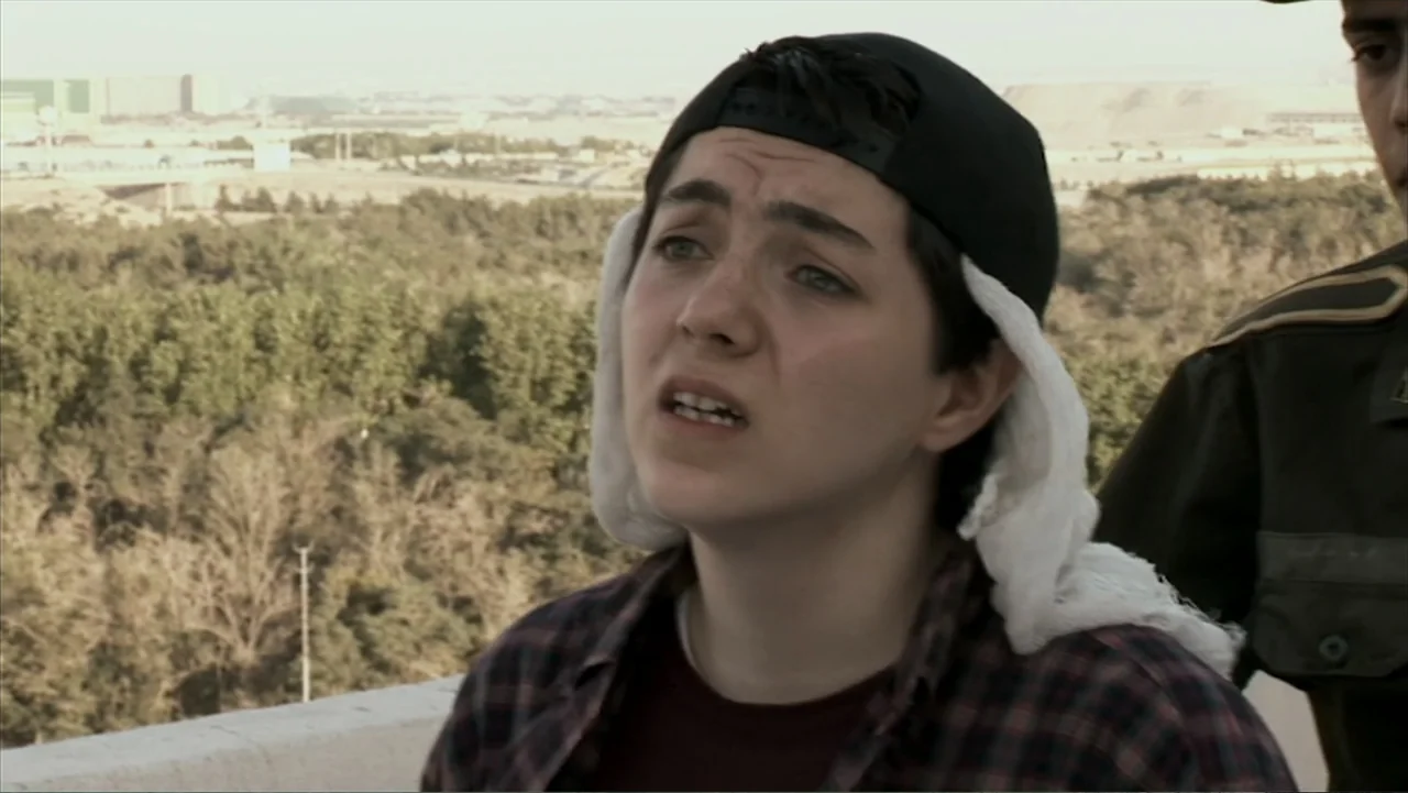 Offside (2015) movie still: closeup — A rooftop terrace overlooks a distant industrial area with sparse trees and buildings. A young person looks…