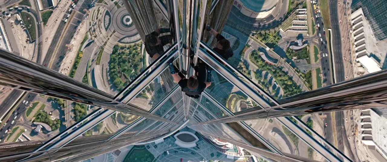 Mission: Impossible – Ghost Protocol (2011) movie still: wide — A man climbs the exterior glass facade of a towering skyscraper from a high…