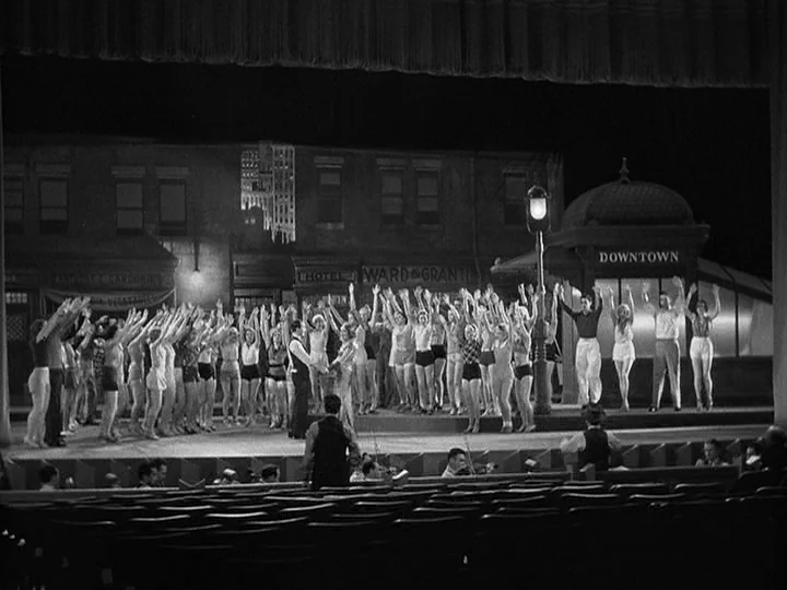 42nd Street (1933) movie still: wide — A wide theater stage depicts a painted backdrop of a city street at night. A large chorus line of dancers in…