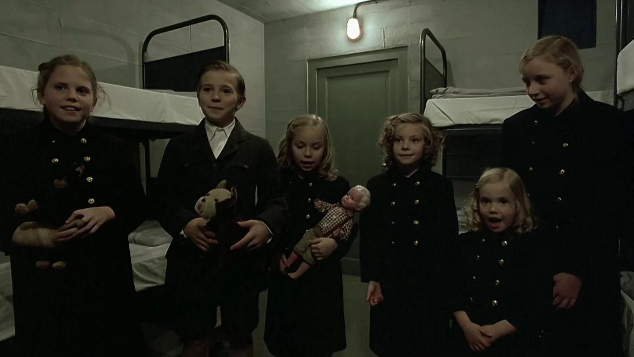 Downfall (2004) movie still: medium — A austere dormitory features concrete block walls and metal bunk beds with white linens. Six children in…