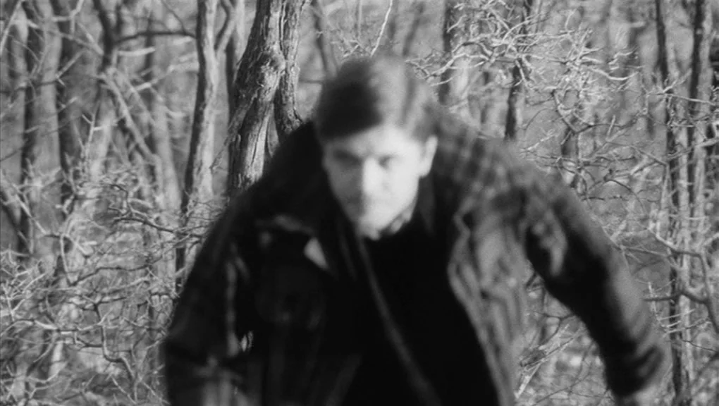 Who’s That Knocking At My Door (1967) movie still: medium — A dense patch of bare, leafless winter trees stands in the background. A man moves…