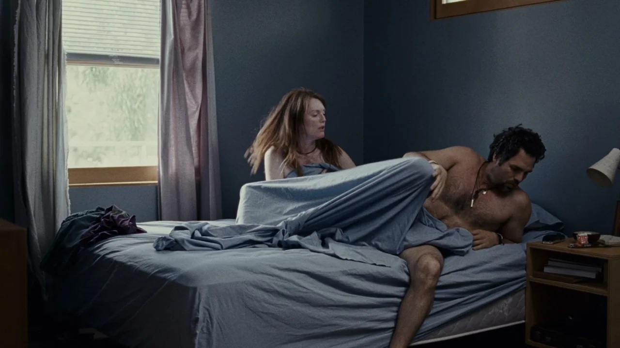 The Kids Are All Right (2010) movie still: medium — A spare bedroom features dark blue walls, a bed with grey linens, and window curtains. A man and…