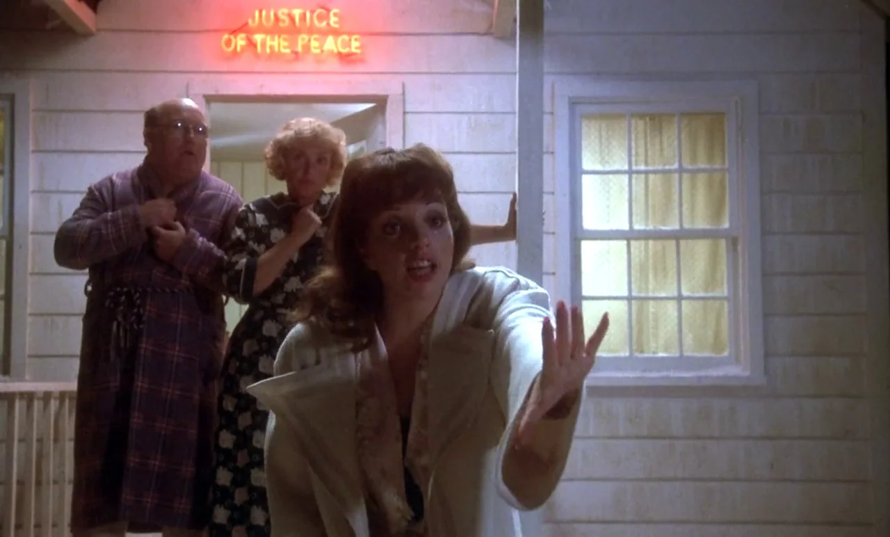 New York, New York (1977) movie still: medium — A wooden building exterior at night features a glowing red neon Justice of the Peace sign. Three…