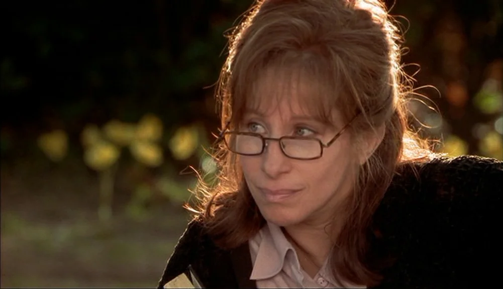 The Mirror Has Two Faces (1996) movie still: closeup — A woman sits outside during the golden hour with soft sunlight framing her head. She wears…