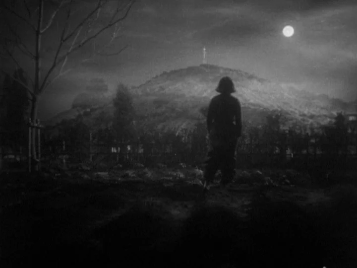 The Most Beautiful (1944) movie still: wide — A dark, open field under a full moon with a distant hill. A lone figure stands facing the hill at night.