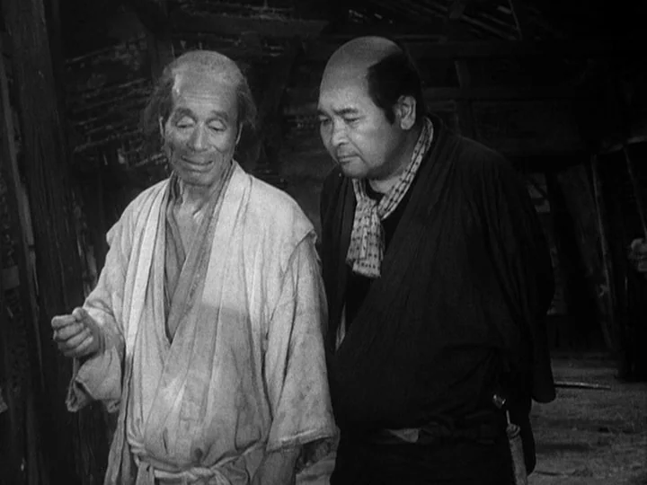The Lower Depths (1957) movie still: medium — A dark, wood-paneled interior contains two men in traditional Japanese clothing standing side-by-side.…