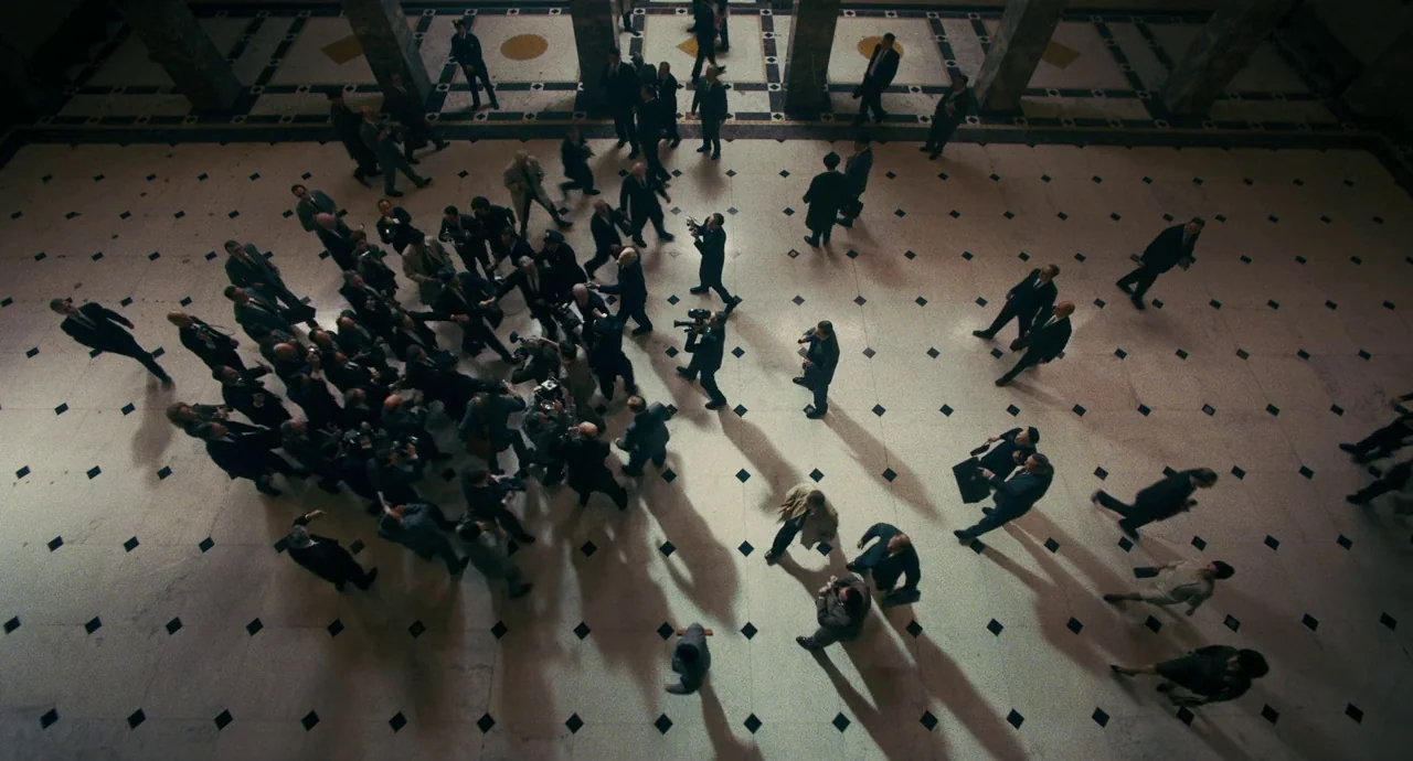 The Irishman (2019) movie still: wide — A spacious marble lobby floor features a geometric diamond pattern of black and white tiles. A large crowd…