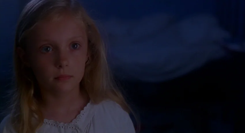 The Secret Of Roan Inish (1994) movie still: closeup — A dark, dimly lit bedroom at night with deep blue ambient shadows. A young blonde girl looks…
