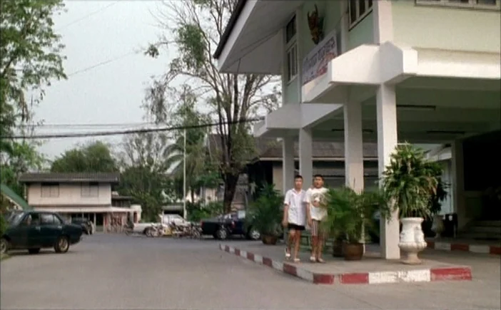 Blissfully Yours (2002) movie still: wide — A light green institutional building features a covered walkway supported by concrete pillars. Two young…