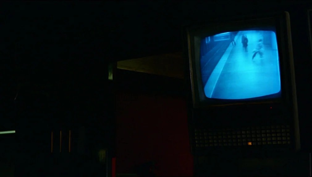 The American Friend (1977) movie still: medium — A dark, dimly lit security room features a single mounted CRT television screen. The monitor…