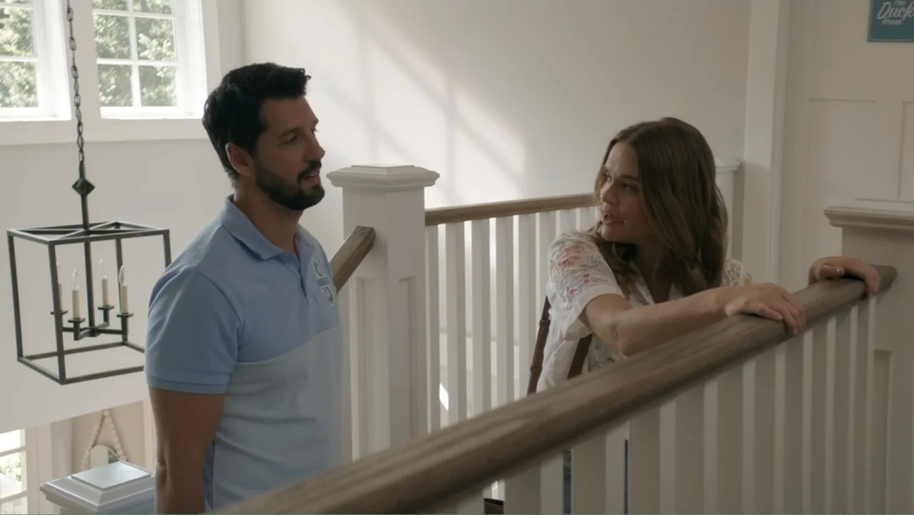 Making Waves (1998) movie still: medium — A residential staircase landing with white railings and walls bathed in bright daylight. A man in a blue…