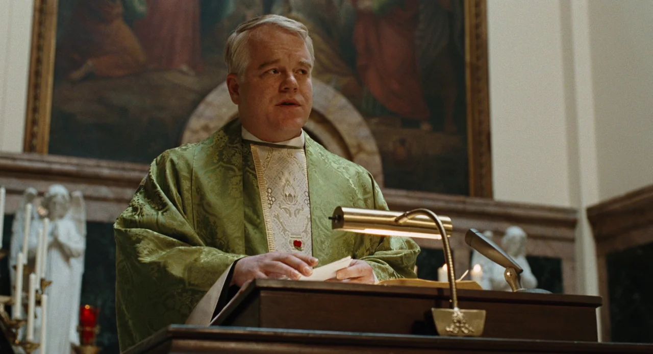 Doubt (2008) movie still: medium — A church interior features an ornate altar with statues and a large religious painting. A priest wearing green…