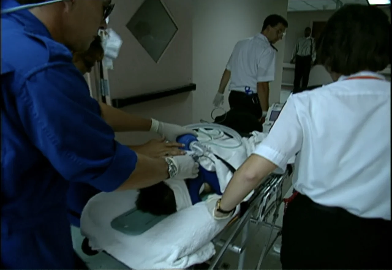 Broken Child (2000) movie still: medium — A hospital corridor with pale walls and institutional features contains an emergency response team.…