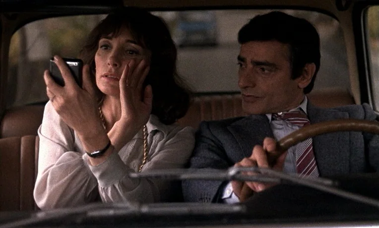 The Man Who Loved Women (1977) movie still: medium — A vintage car interior features brown vinyl seats and a classic steering wheel. A woman…