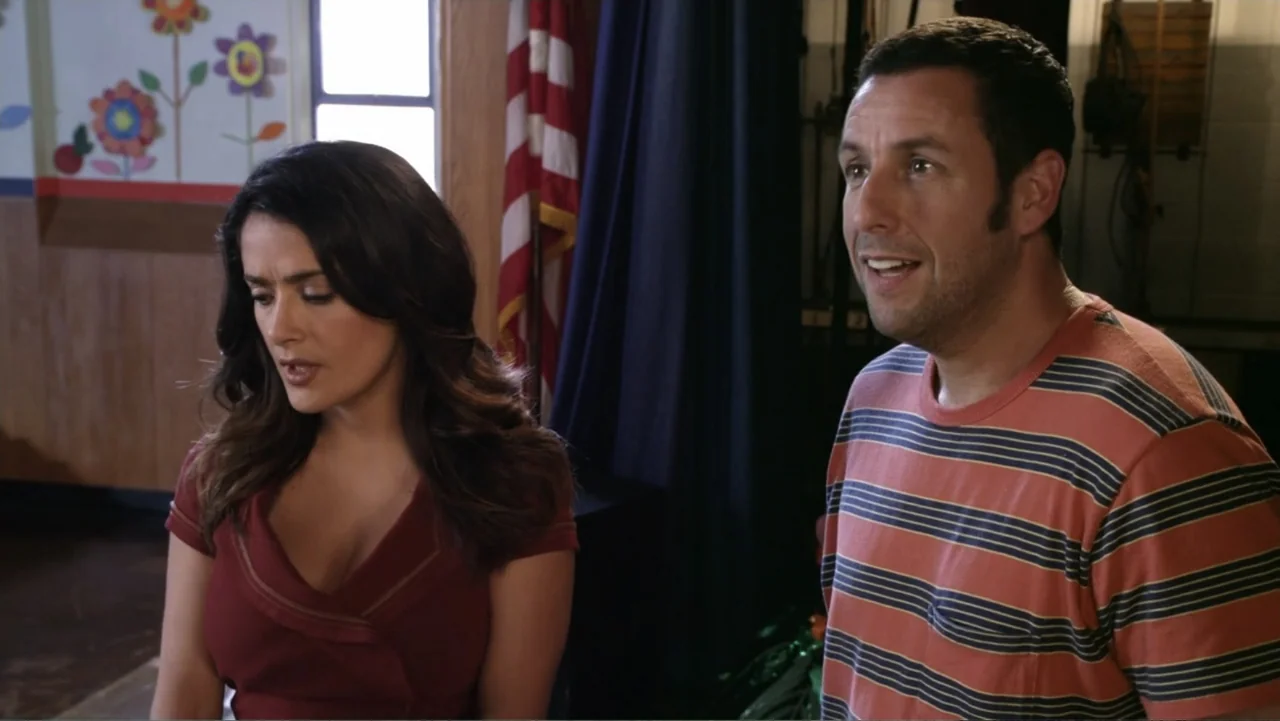 Grown Ups 2 (2013) movie still: medium — A community center room features a wall decorated with colorful paper flower cutouts. A man and a woman…