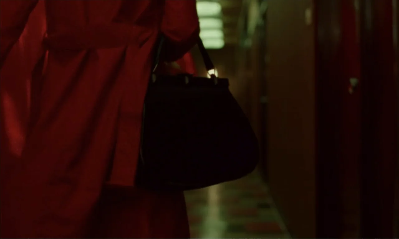 In the Mood for Love (2000) movie still: medium — A dimly lit hotel corridor features red walls and a receding perspective of fixtures. A figure in…