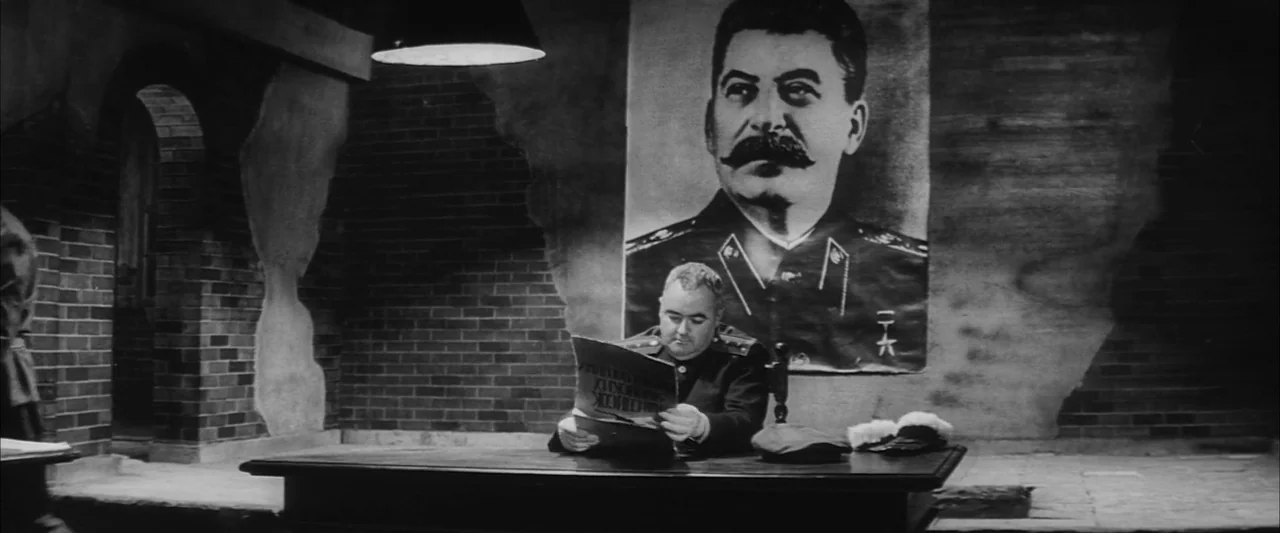 The Human Condition III: A Soldier’s Prayer (1961) movie still: medium — A spartan office with exposed brick walls and an oversized portrait of…