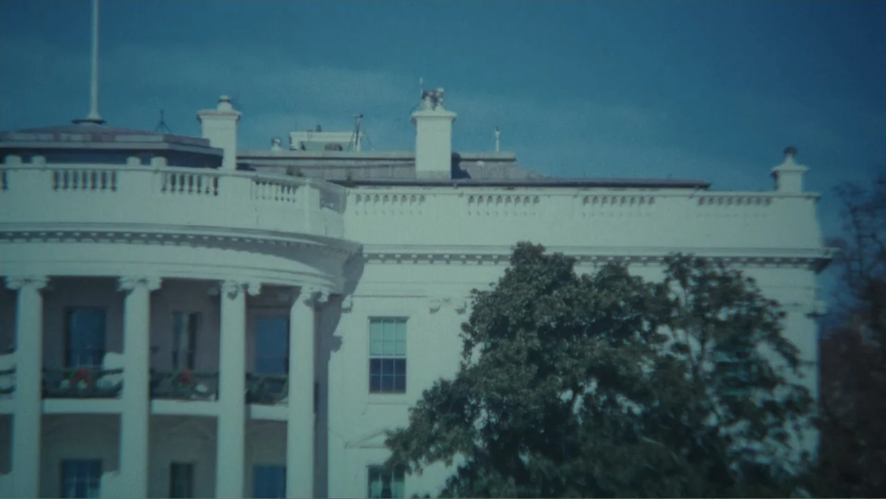 Demon in the White House (2021) movie still: establishing — The exterior facade of a large white neoclassical building features columns and…
