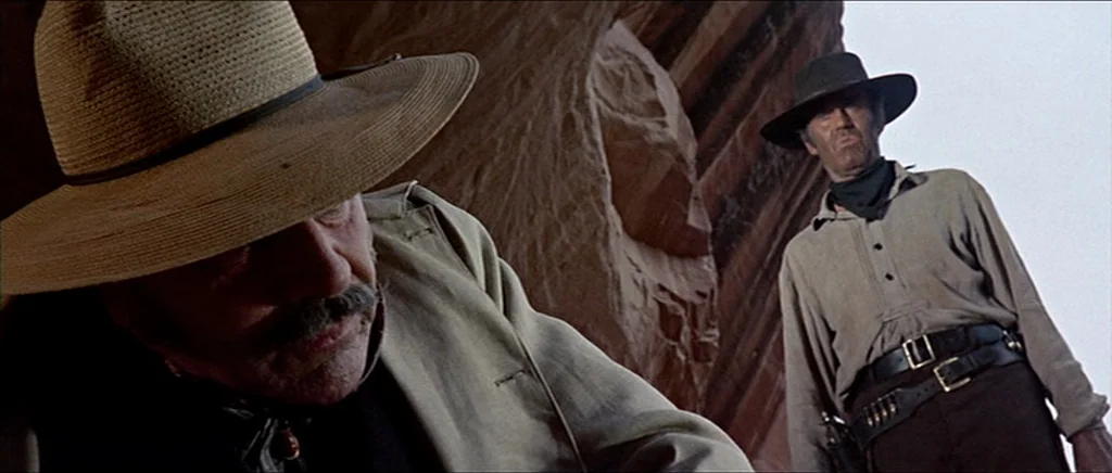 Once Upon A Time In The West (1968) movie still: medium — A rugged desert canyon features towering red sandstone walls behind two men. The…
