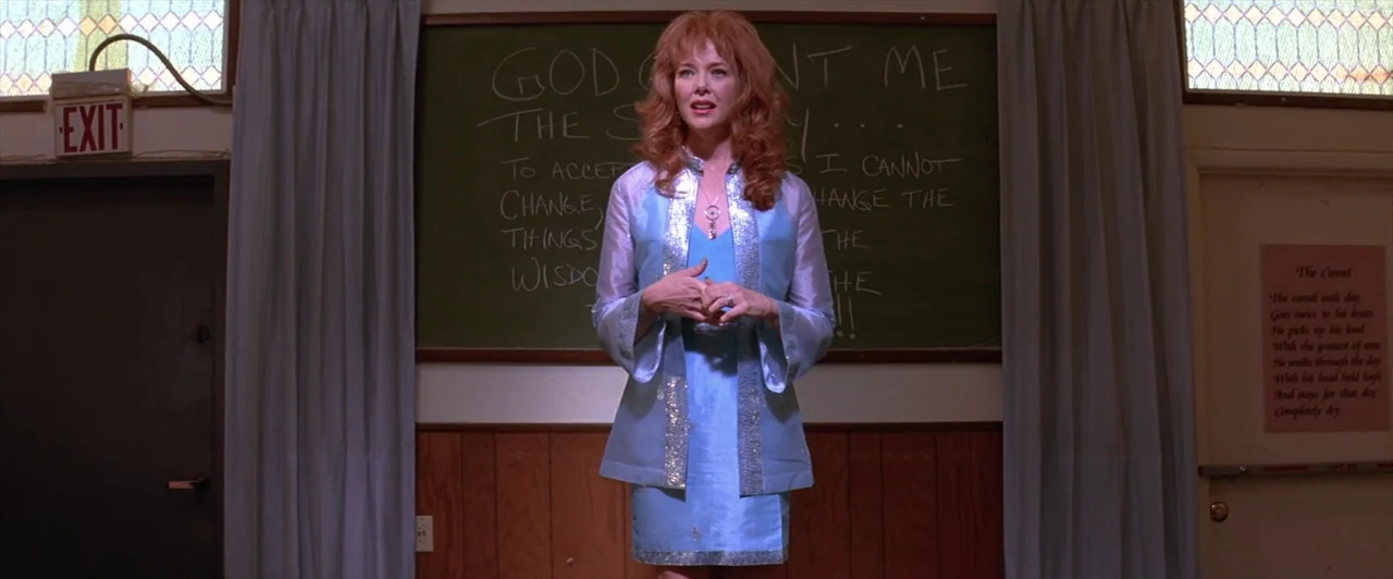 Mars Attacks! (1996) movie still: medium — A room with wooden paneling and a large green chalkboard covered in chalk writing. A woman in a blue…