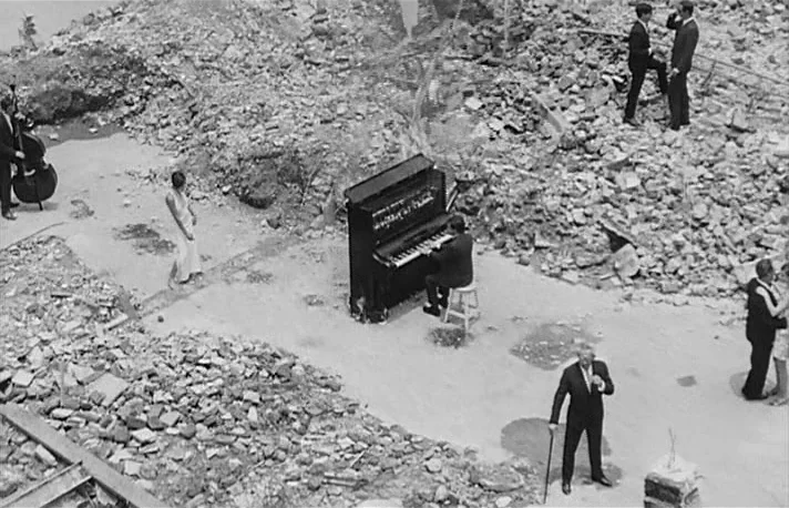 Fando y Lis (1968) movie still: wide — A field of broken stone and building rubble creates an open, desolate outdoor site. A group of formally…