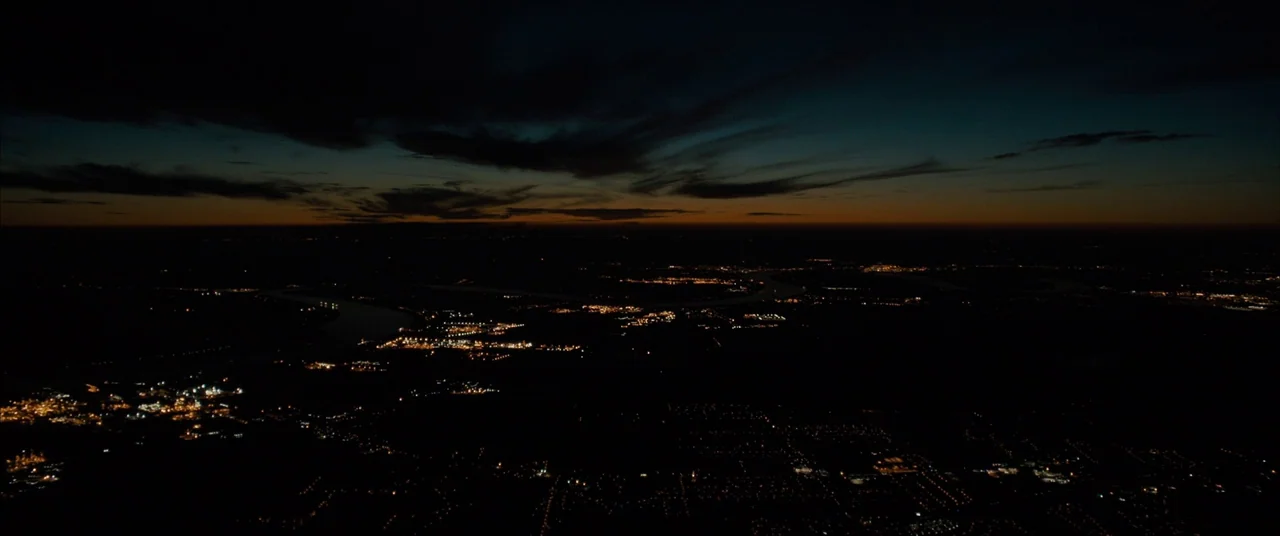 Midnight Special (2016) movie still: establishing — An aerial view of a dark landscape with clustered city lights dotting the terrain. A distant…