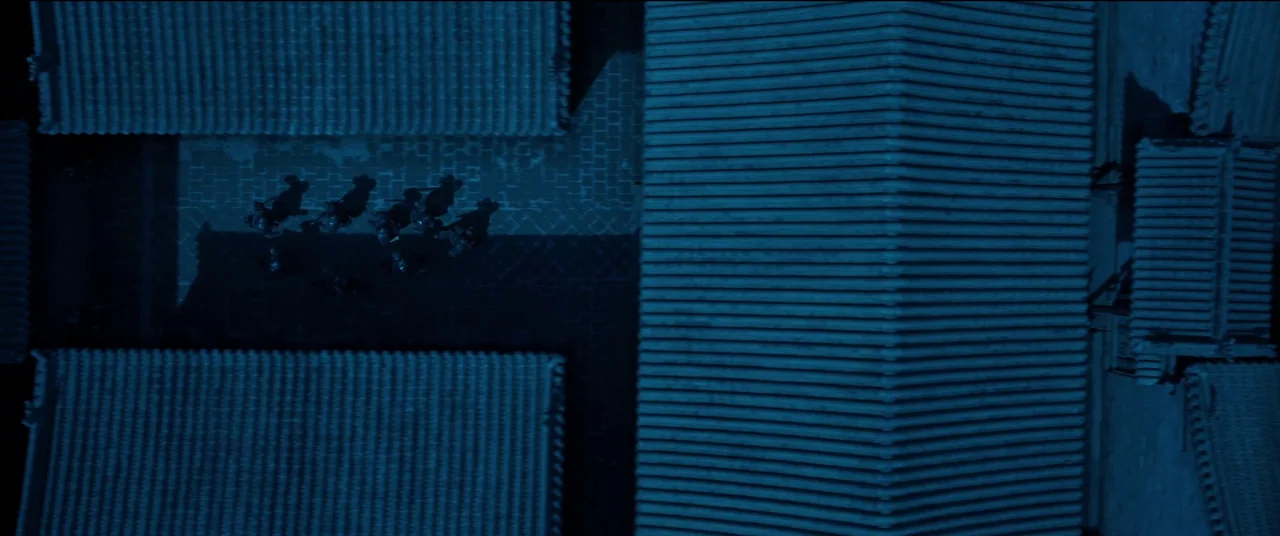 Full River Red (2023) movie still: wide — An aerial view shows a traditional courtyard between long tiled roof buildings at night. A small group of…