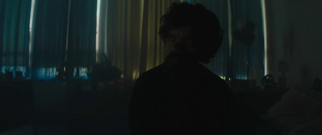 I Think We’re Alone Now (2018) movie still: medium — A dimly lit room features a subject framed against tall, backlit curtains at night. The man…