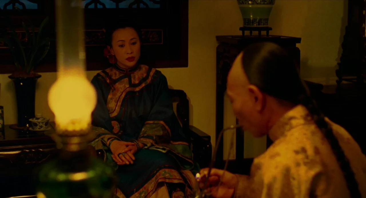 Flowers of Shanghai (1998) movie still: medium — A dimly lit room features traditional Asian furniture including a carved wooden pedestal table. A…