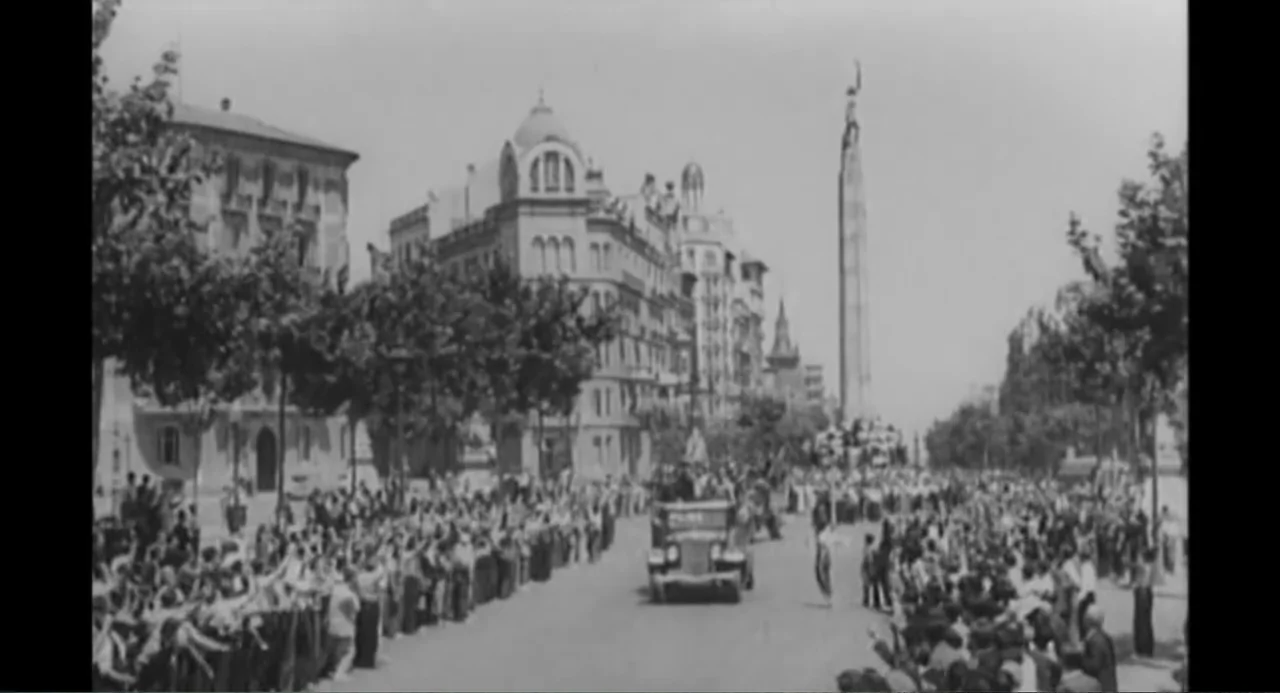 Az X- Kryptonit projekt (2020) movie still: establishing — A wide view of a broad city avenue lined with mature trees and stone buildings. People…