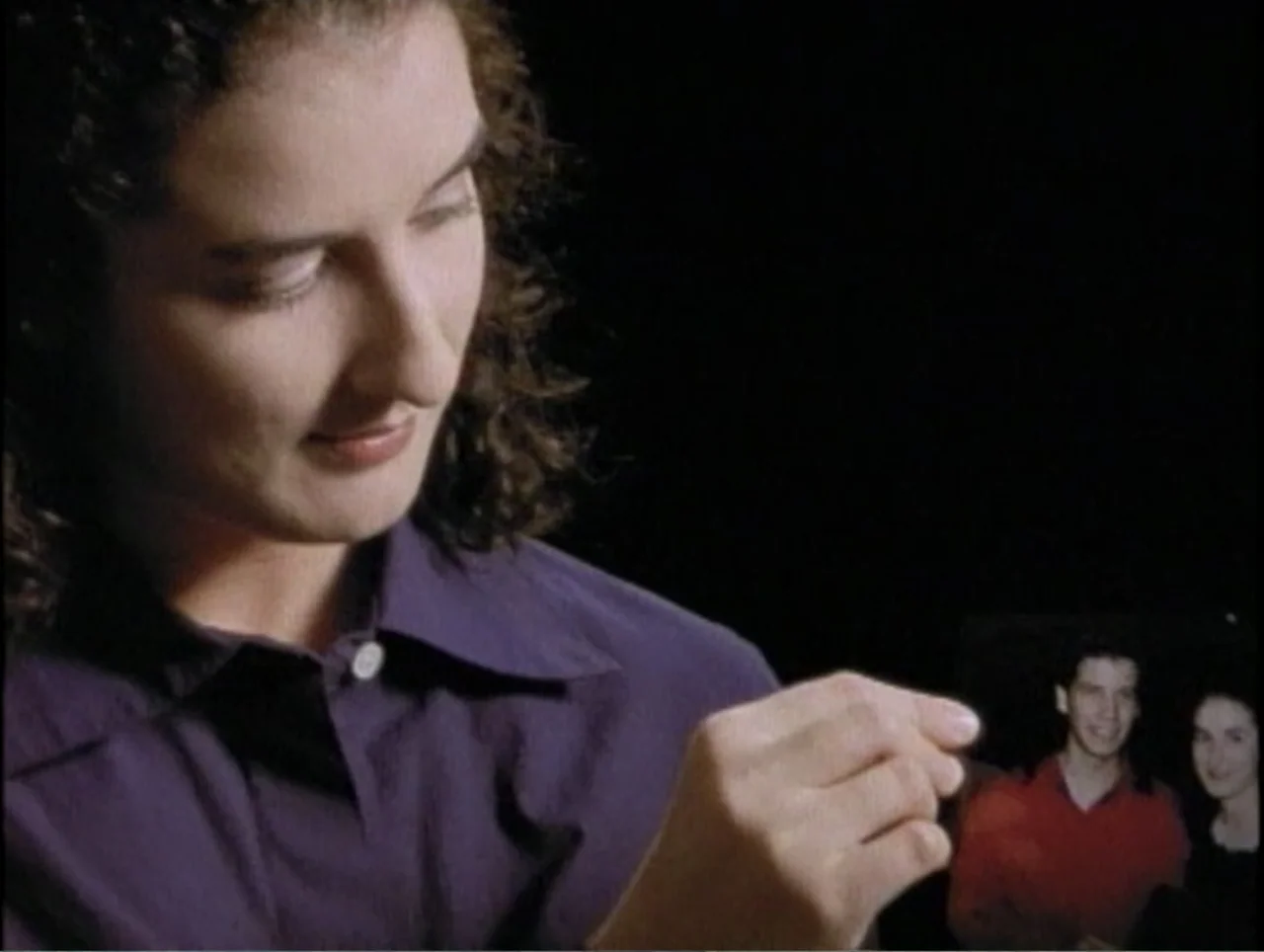 America Undercover: Life Afterlife (2000) movie still: closeup — A dark, unidentifiable indoor space with minimal ambient light. A young woman…