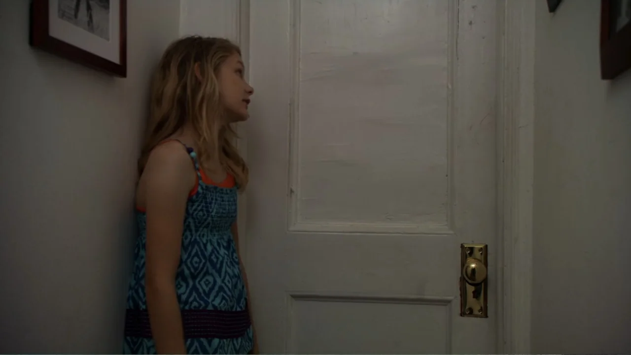Jeremy Fink and the Meaning of Life (2012) movie still: medium — A narrow residential hallway with white walls and a closed door. A teenage girl…