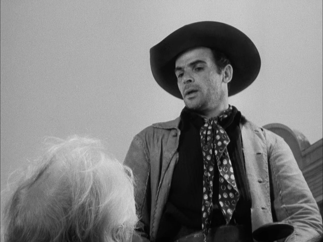The Ox-Bow Incident (1942) movie still: medium — A man in a western hat stands in a bright, sunlit outdoor desert environment. He looks down toward…