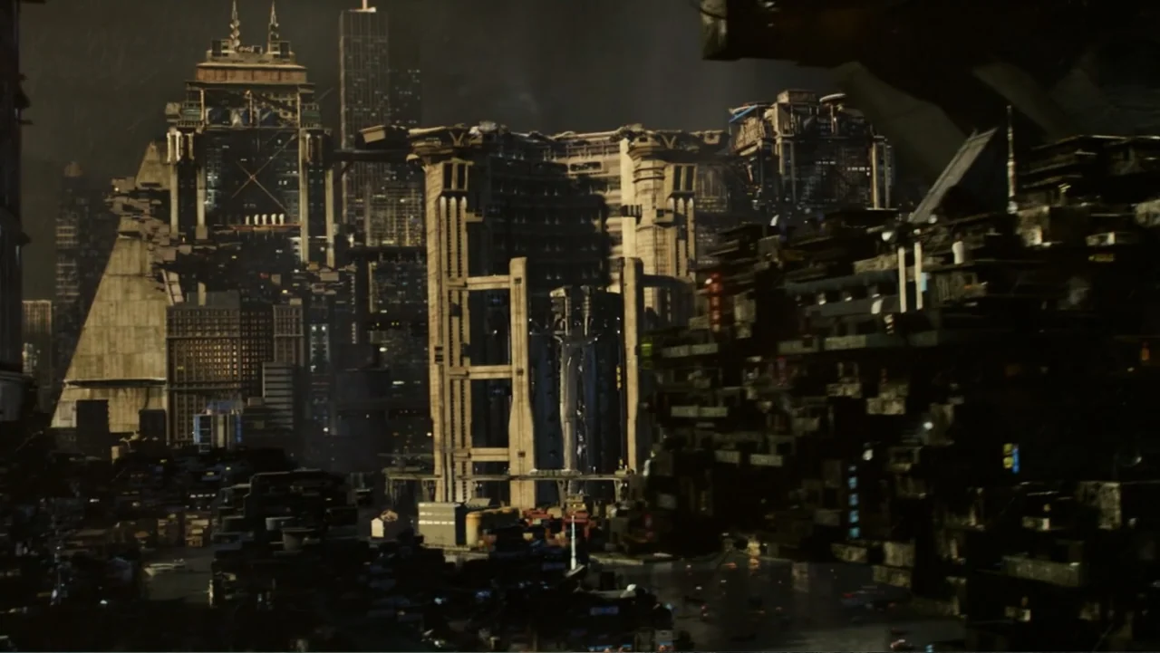 Total Recall (2012) movie still: establishing — A dark futuristic city features massive concrete structures and towering industrial skyscrapers at…