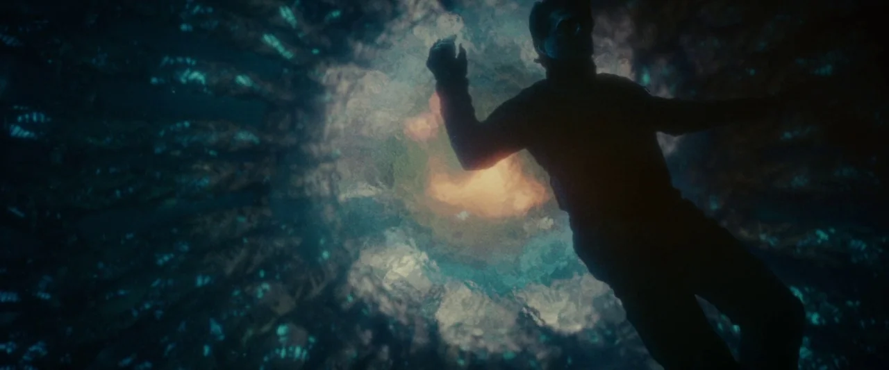 Edge of Tomorrow (2014) movie still: medium — A dark, twisting tunnel composed of organic, glowing blue matter surrounds a floating person. The…