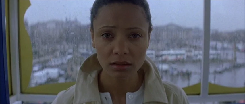 The Truth About Charlie (2002) movie still: closeup — A woman sits inside a glass-walled ferris wheel cabin during a rainy day. She faces the camera…