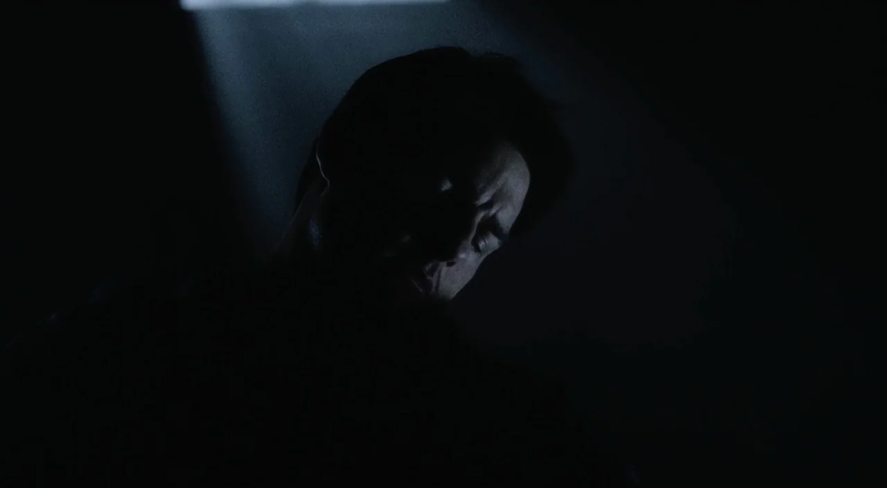 War of the Worlds (2005) movie still: closeup — A person is situated in a nearly black environment with almost no background visible. A man looks…
