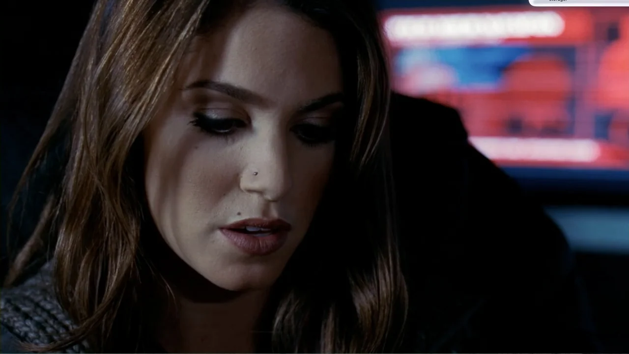 Chain Letter (2010) movie still: closeup — A dark, dimly lit workstation is dominated by the glow of a computer monitor. A young woman with brown…