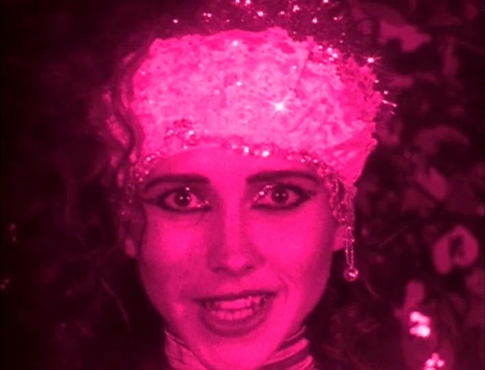Tales from the Gimli Hospital (1988) movie still: closeup — A close portrait of a woman wearing an ornate, reflective sequined headpiece on stage.…