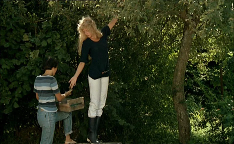 Pauline At the Beach (Pauline à la plage) (1983) movie still: fullbody — An orchard setting with dense foliage and a tree in the mid-ground. Two…