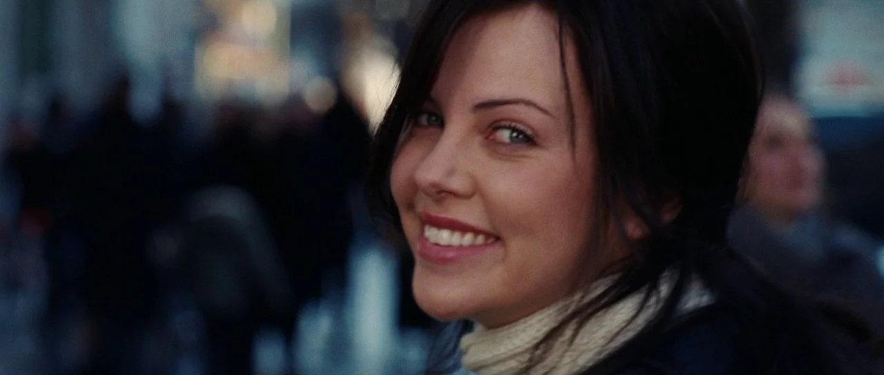 Aeon Flux (2005) movie still: closeup — A crowded public thoroughfare with blurred figures in the background. A woman in a knit sweater turns to…