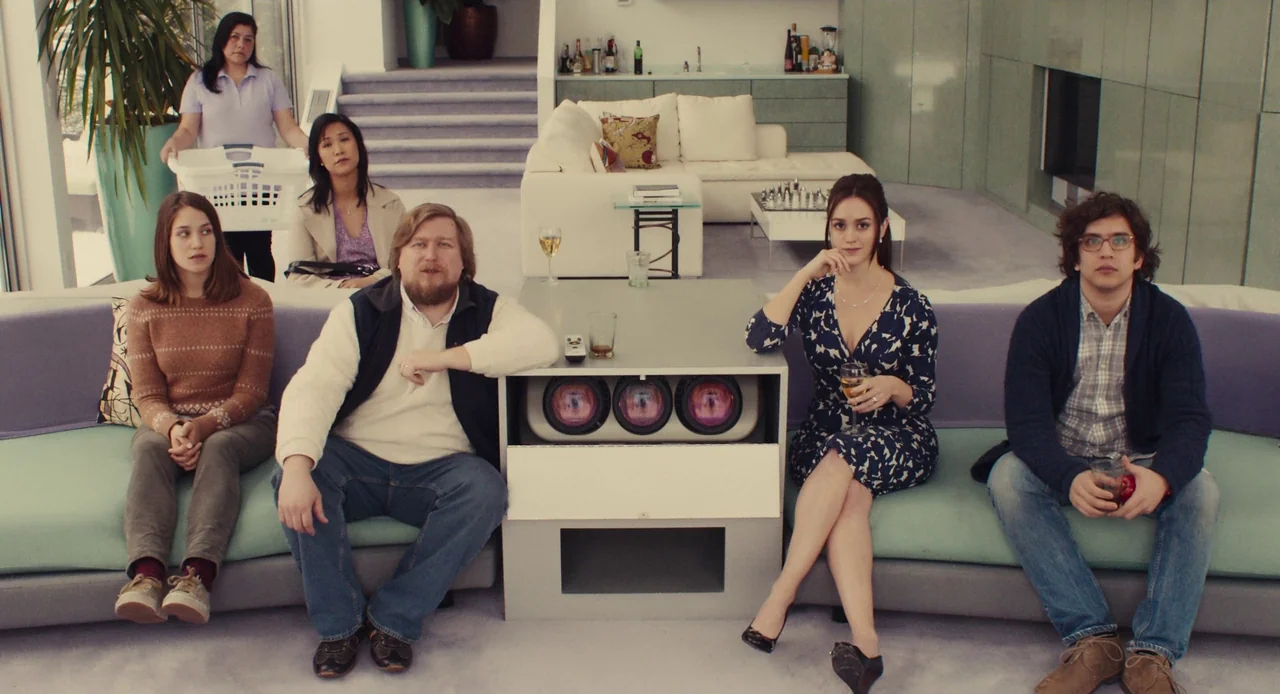 Mistress America (2015) movie still: wide — A wide, open-plan modern living space features geometric furniture and soft carpeting. Six individuals…