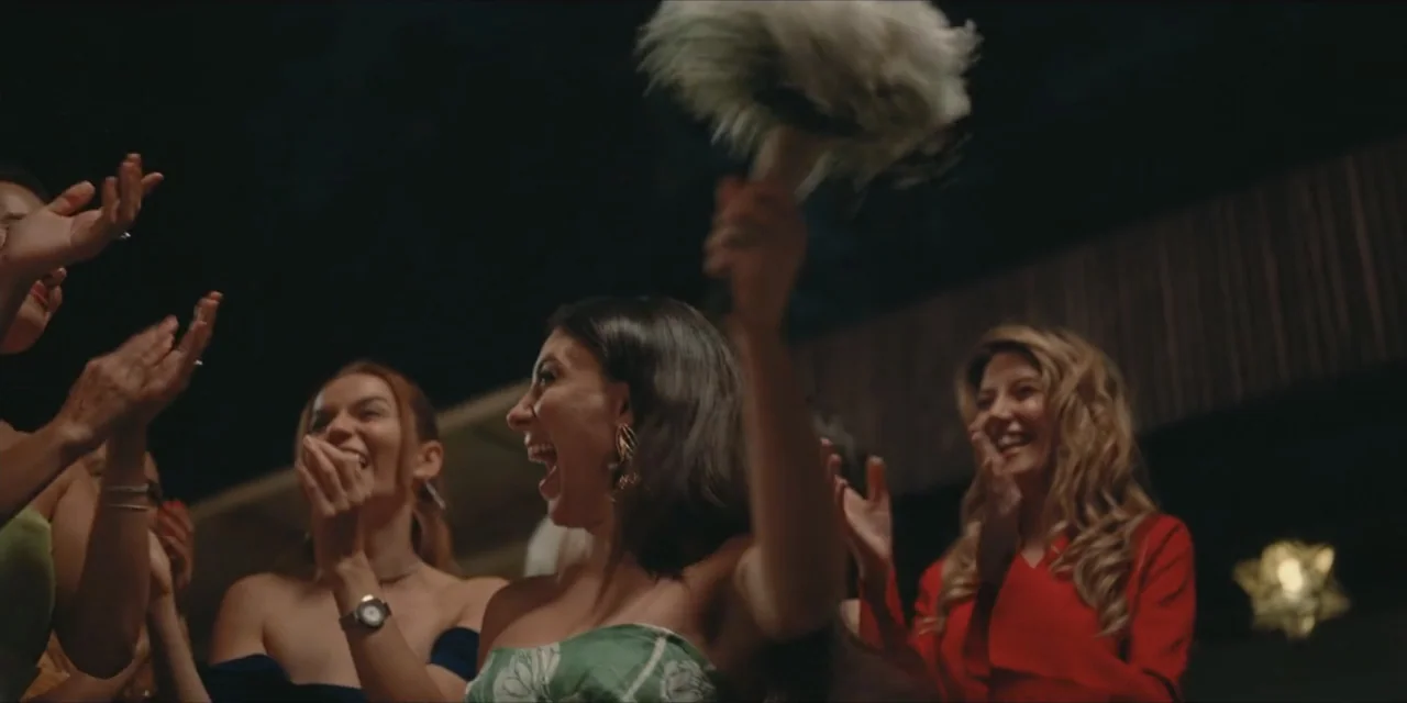 Kill Me If You Dare (2019) movie still: medium — An outdoor evening gathering features several women celebrating and clapping under dark skies. The…