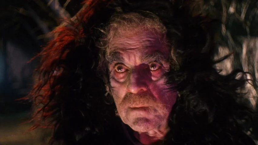 Black Sabbath (1963) movie still: closeup — An elderly person sits in a dimly lit, shadowy environment with textured dark surroundings. The subject…