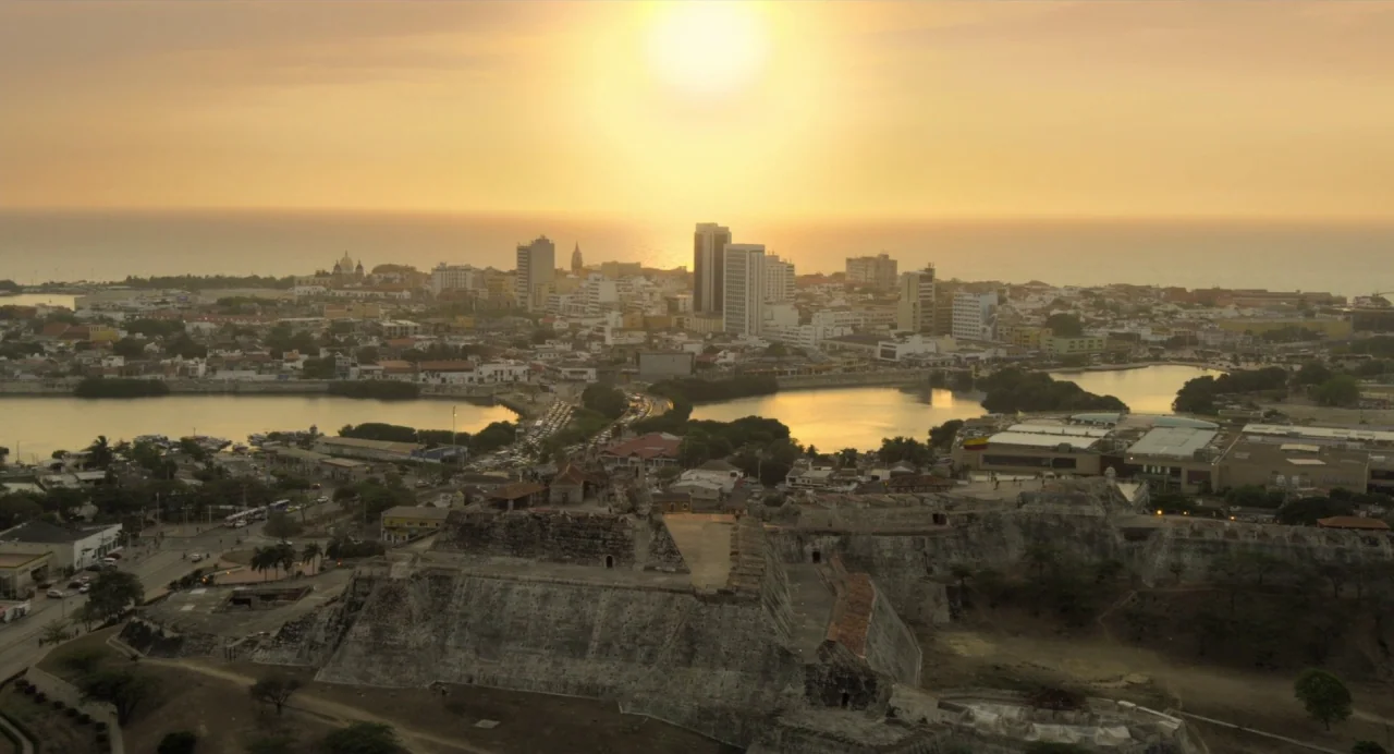 Gemini Man (2019) movie still: establishing — An aerial view shows a sprawling coastal city featuring a historic stone fortress. The sun hangs low…