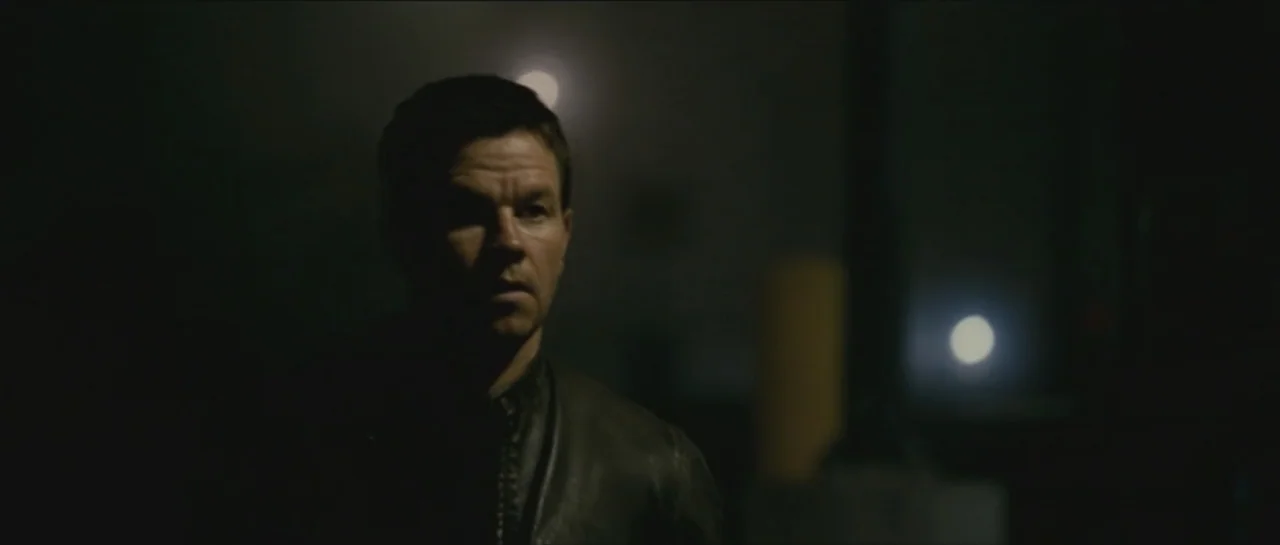 Contraband (2012) movie still: medium — A dark, blurred outdoor street area at night with distant out-of-focus streetlights. A man in a dark leather…